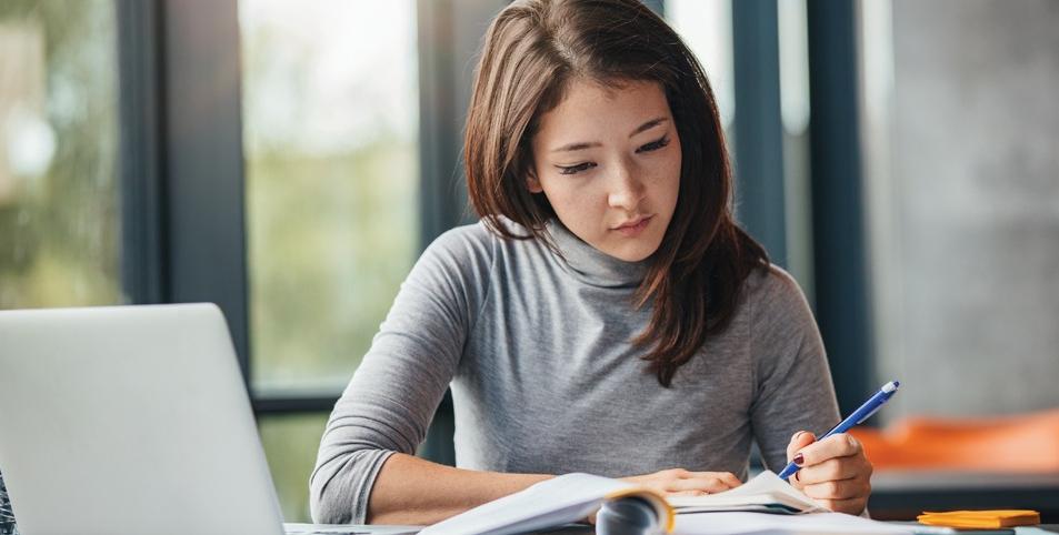 年轻女子在日记中记笔记的镜头. 女大学生在图书馆准备考试笔记.